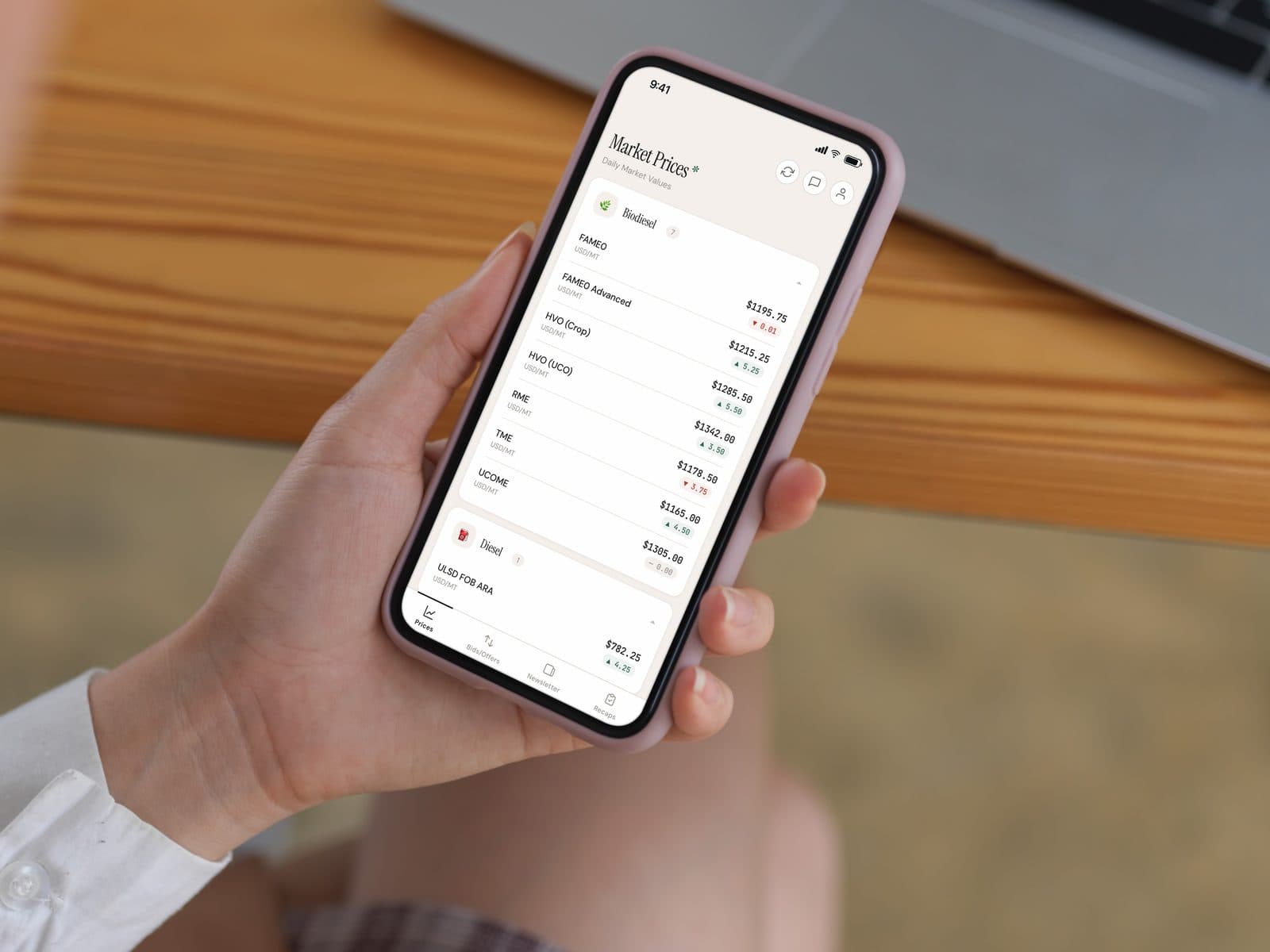 A phone in someone's hand at a desk, open on the Bardi Fuels app's daily market prices screen